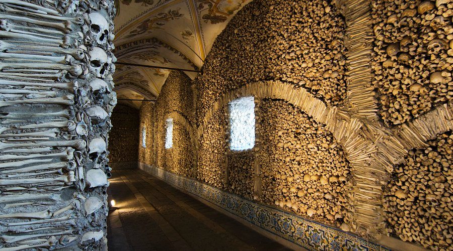 Murs et colonnes de la Capela dos Ossos d'Évora entièrement recouverts de crânes et d'ossements humains disposés en motifs