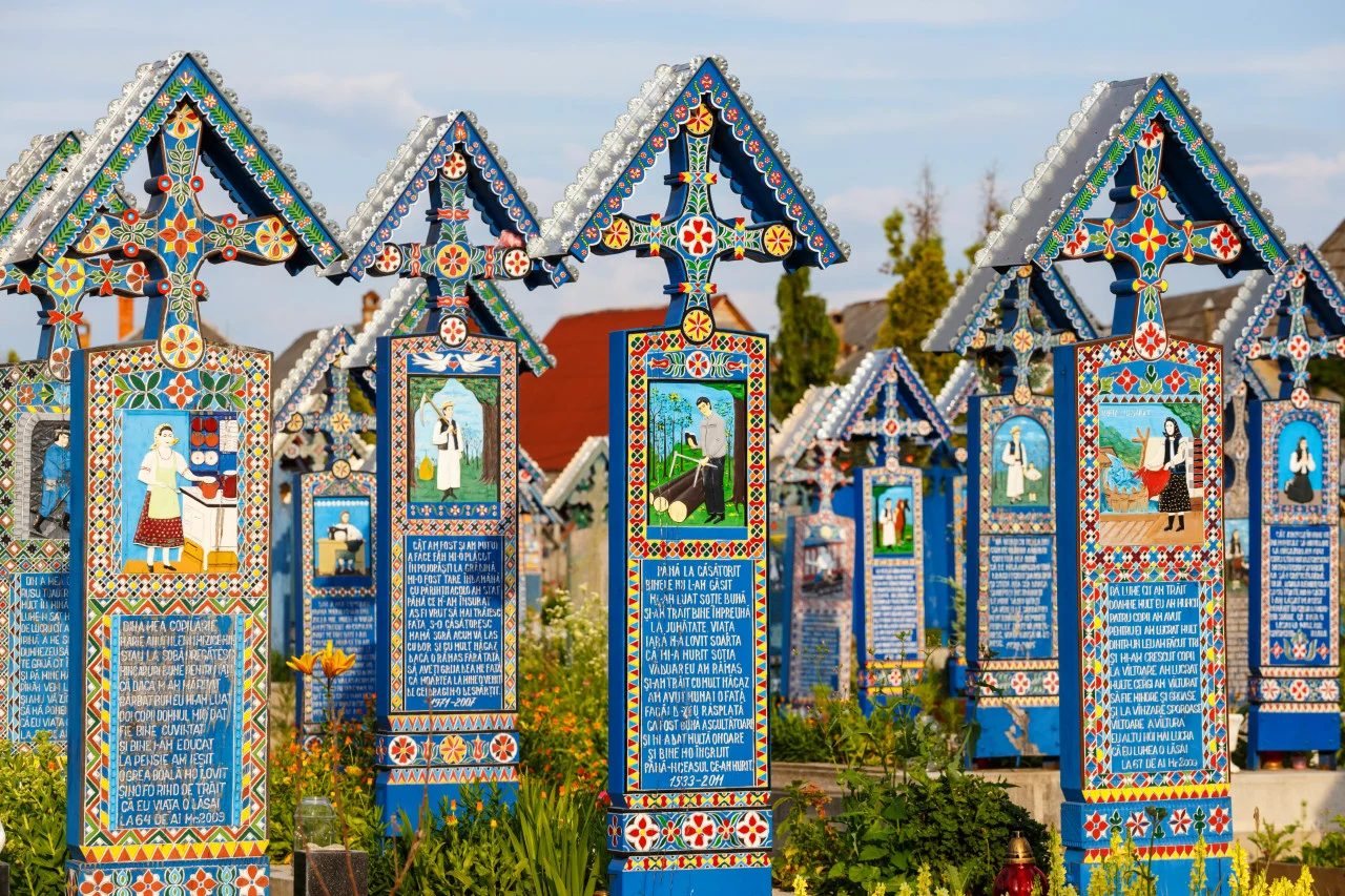 Croix funéraires en bois peintes en bleu vif et ornées de scènes naïves colorées au Cimetière joyeux de Săpânța