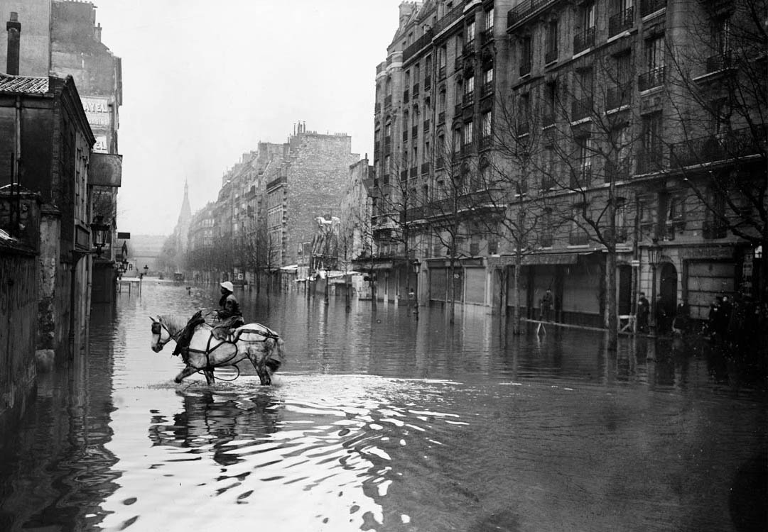 Une rue de Paris inondée lors de la grande crue de la Seine de janvier 1910, avec des passerelles de bois au-dessus de l'eau