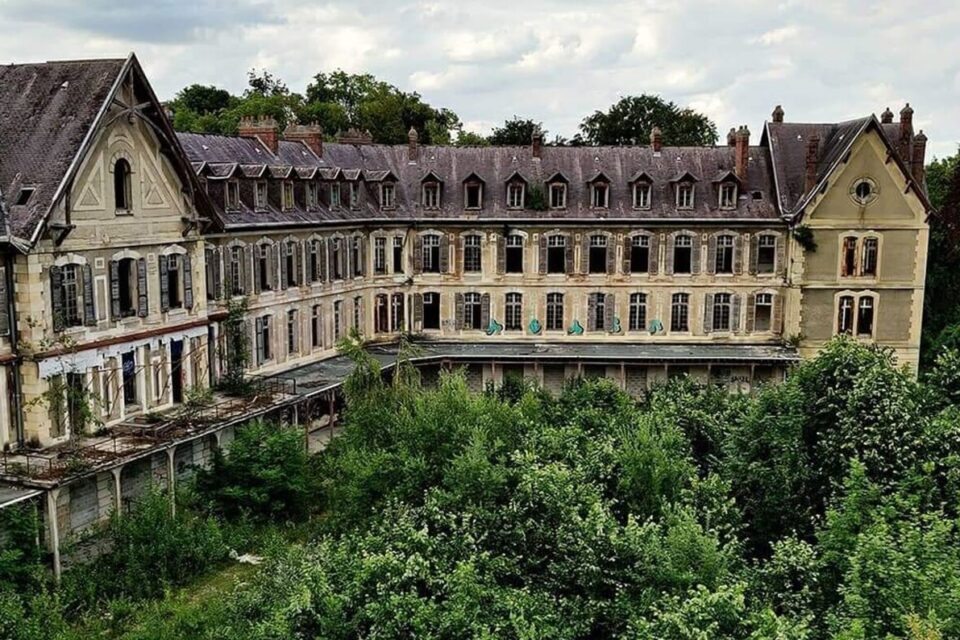 Les bâtiments en briques rouges abandonnés de l'hôpital Villemin d'Angicourt, envahis par la végétation dans l'Oise