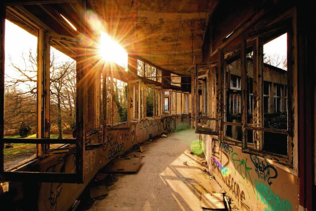 Explorateur urbain photographiant l'intérieur d'un bâtiment industriel abandonné, lampe à la main